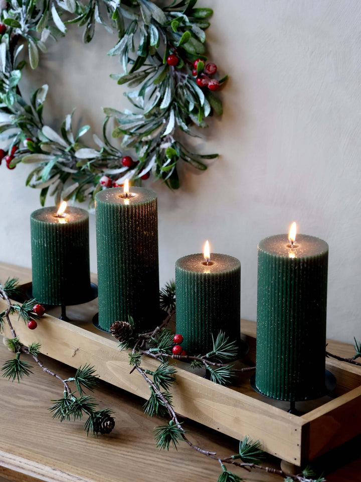 Four Elegant olive green pillar candle with grooves, glowing warmly in a festive table centrepiece 