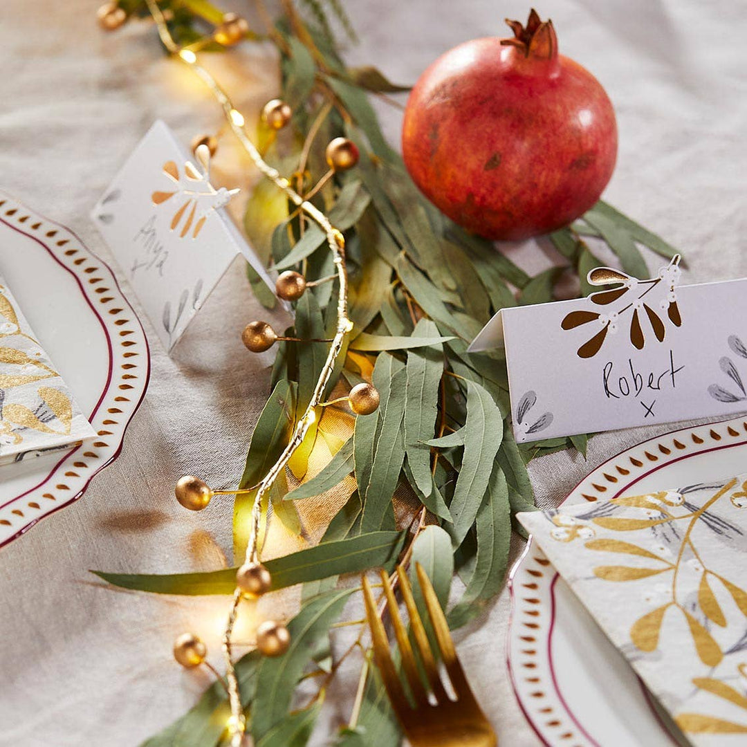 Christmas Gold Berry String of LED Lights, Source for the Goose Devon, illuminating a festive dinner table with elegant decor and pomegranate.