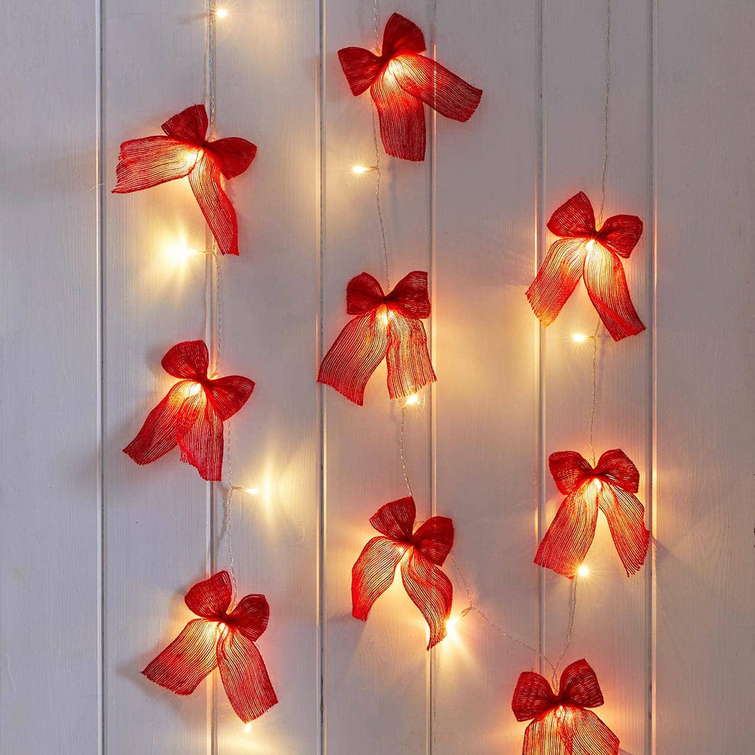 Red Fabric Bow String of LED Lights by Source for the Goose adding whimsical and cosy ambiance to a room, perfect for parties in Devon