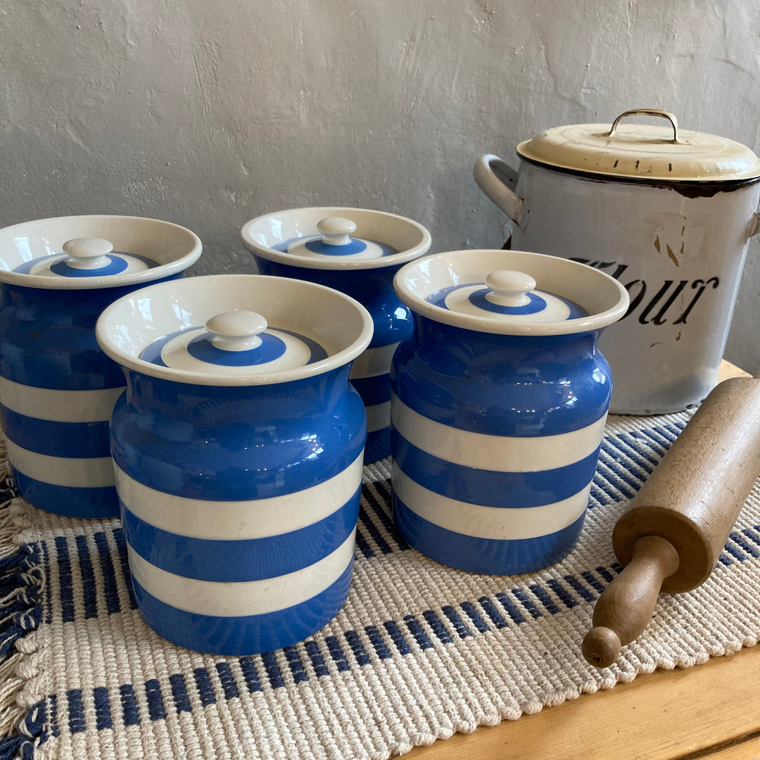 Vintage Cornishware blue and white striped jars with lids on a kitchen counter with a rolling pin and flour container from Source for the Goose, Devon.