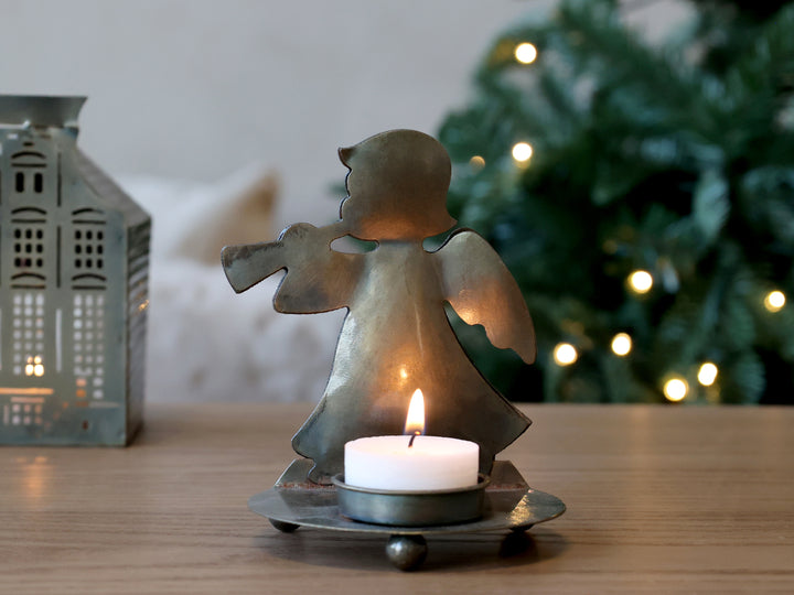 Brass Angel Tea Light Holder illuminating in holiday decor with festive greenery, Source for the Goose Devon.