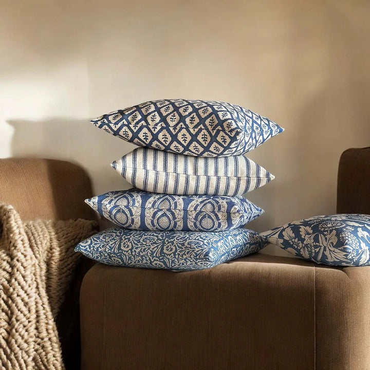 Stack of indigo blue cushions on a sofa, featuring various patterns, enhancing home decor with a vintage touch.