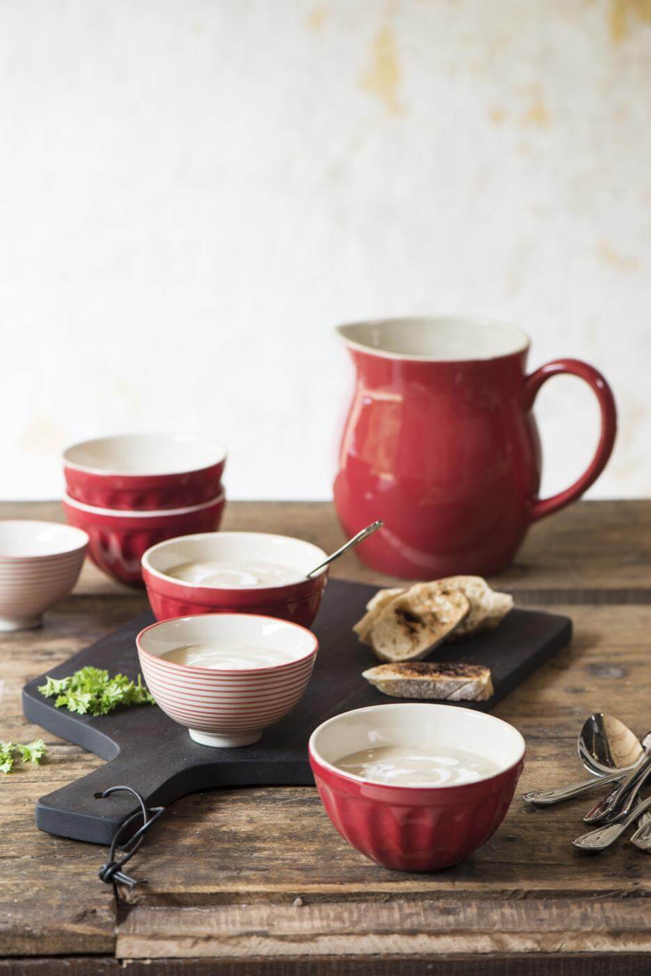 rustic display of red ceramics including small red cereal bowl