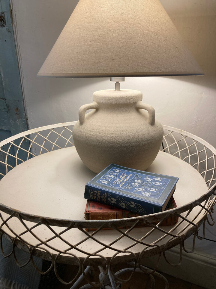 French style metal side table with lamp and decorative books on a light-colored surface. Ideal for home decor.