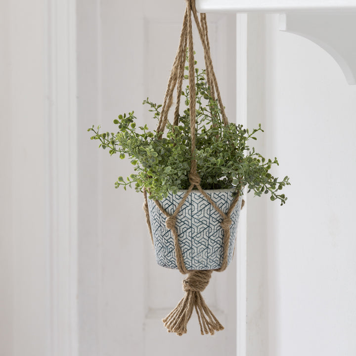 Jute plant hanger with intricate knotting, displaying a green plant in a stylish blue pot, perfect for home decor.