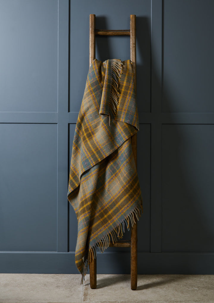 Cottage Check Mustard Wool Throw by Tweedmill draped over a wooden ladder, available at Source for the Goose, Devon.