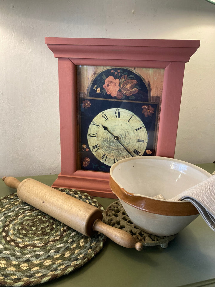 Country style painted wall clock featuring floral design, with a rolling pin and bowl in a charming kitchen setting.