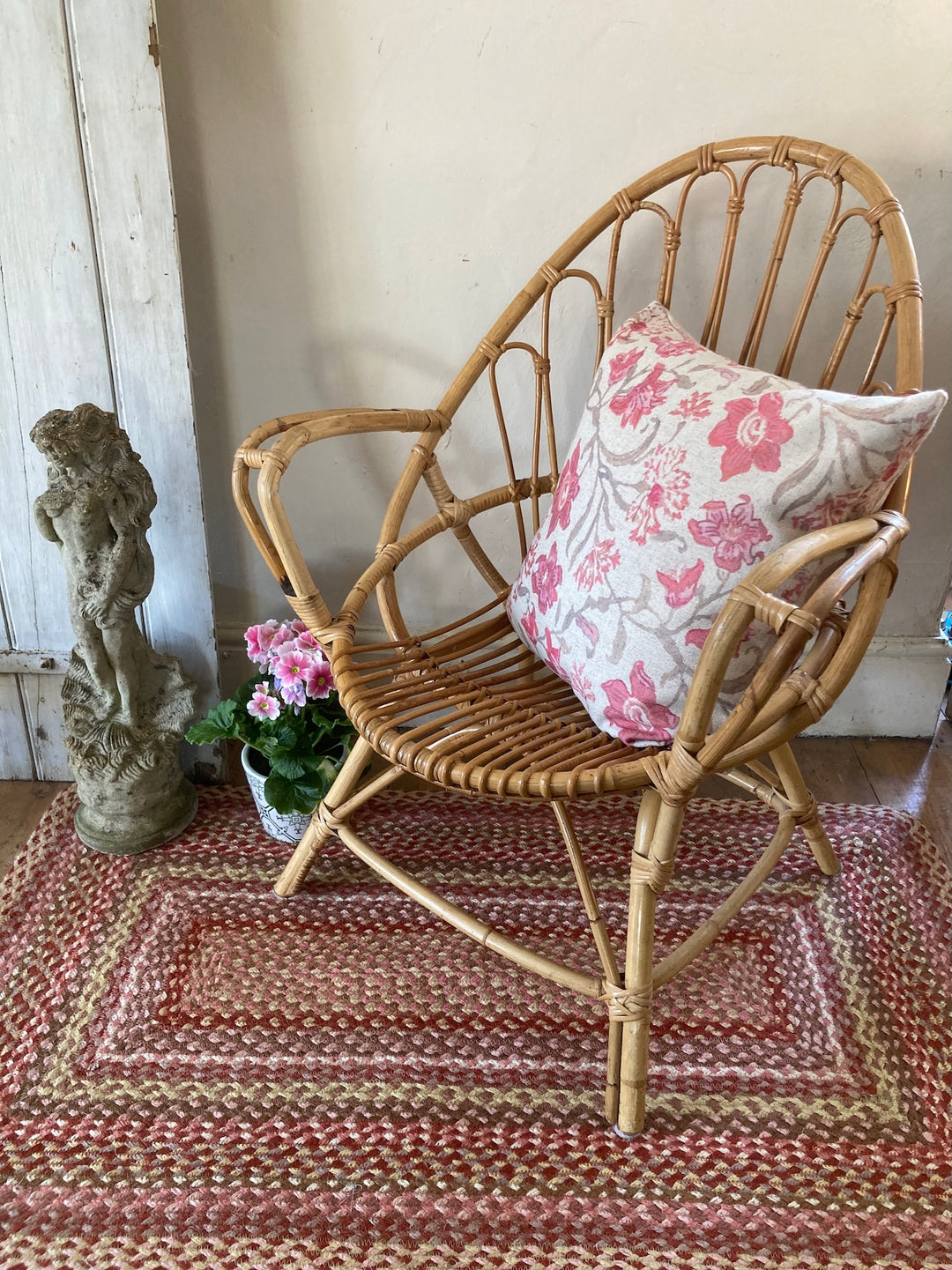 Small wicker chair with arms and floral cushion, perfect for summerhouses or conservatories, Source for the Goose Devon.