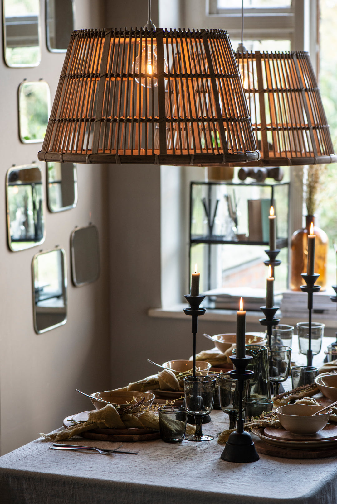 Elegant dining table with black iron candlesticks, wicker lamps, and tableware, creating an inviting atmosphere. Source for the Goose Devon.