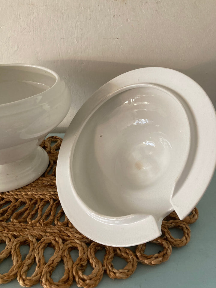 Large antique white tureen and bowl on woven placemat, showcasing rustic farmhouse elegance.