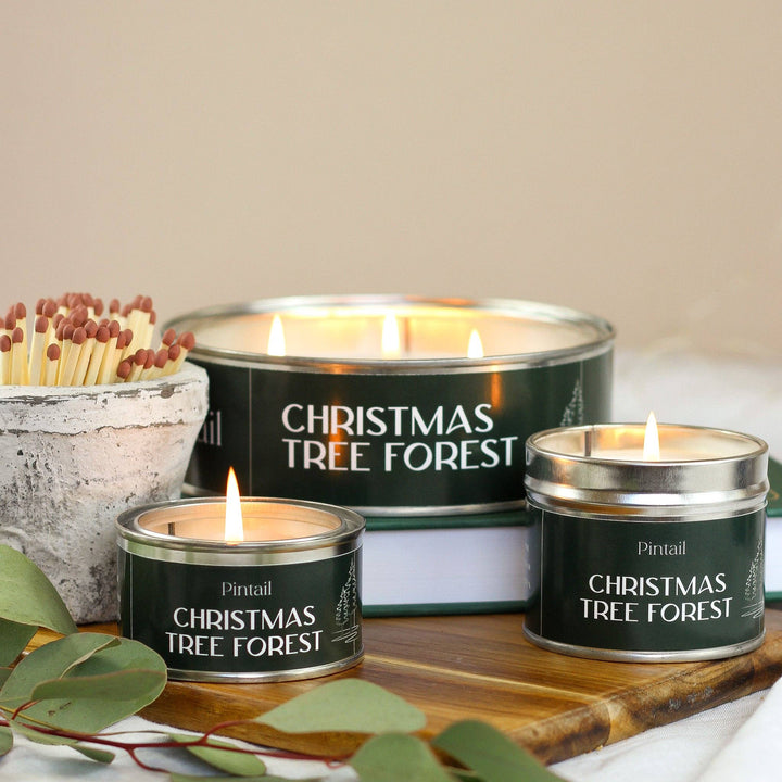 Pintail Candles Christmas Tree Forest tin candles burning with festive ambiance, featuring Source for the Goose Devon products.