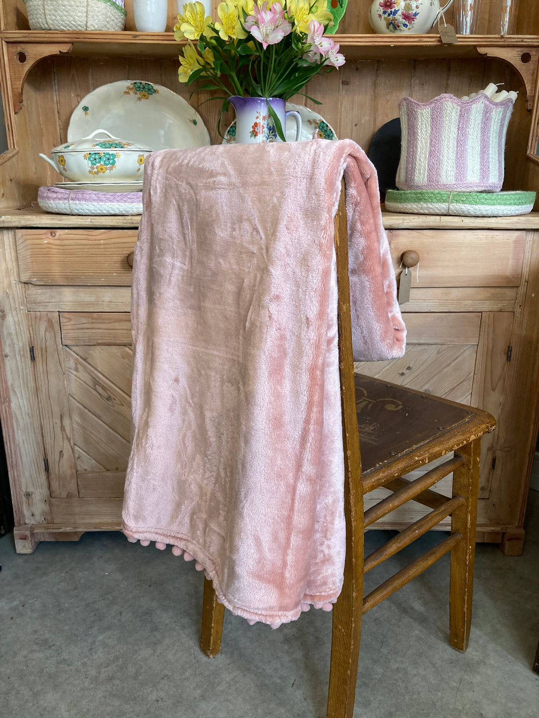 Cashmere Touch Throw in Blush Pink draped over a chair in front of an old pine dresser