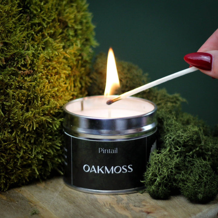 "Hand lighting a Pintail Oakmoss Classic Tin Candle surrounded by moss – autumn aroma, handmade in Cumbria, Source for the Goose Devon"