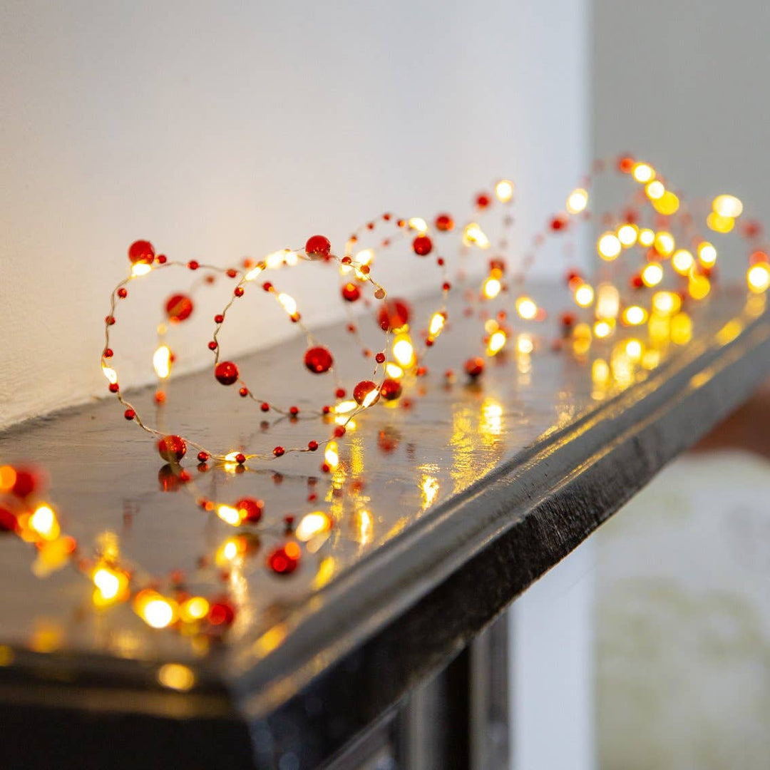 Red Berry Christmas String Lights on mantlepiece, bright LED decorations from Source for the Goose Devon, warm festive gold wire lights.