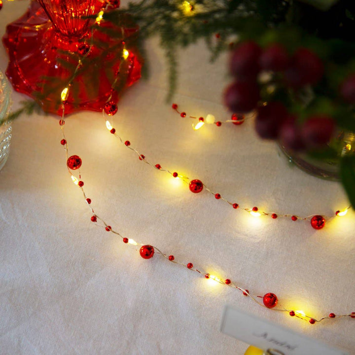 Red Berry Christmas String Lights from Source for the Goose, Devon, arranged on a festive table with gold wire and LED lights