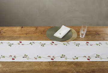 Embroidered Trailing Holly White Table Runner with red berries on wooden table, Source for the Goose Devon holiday decor.