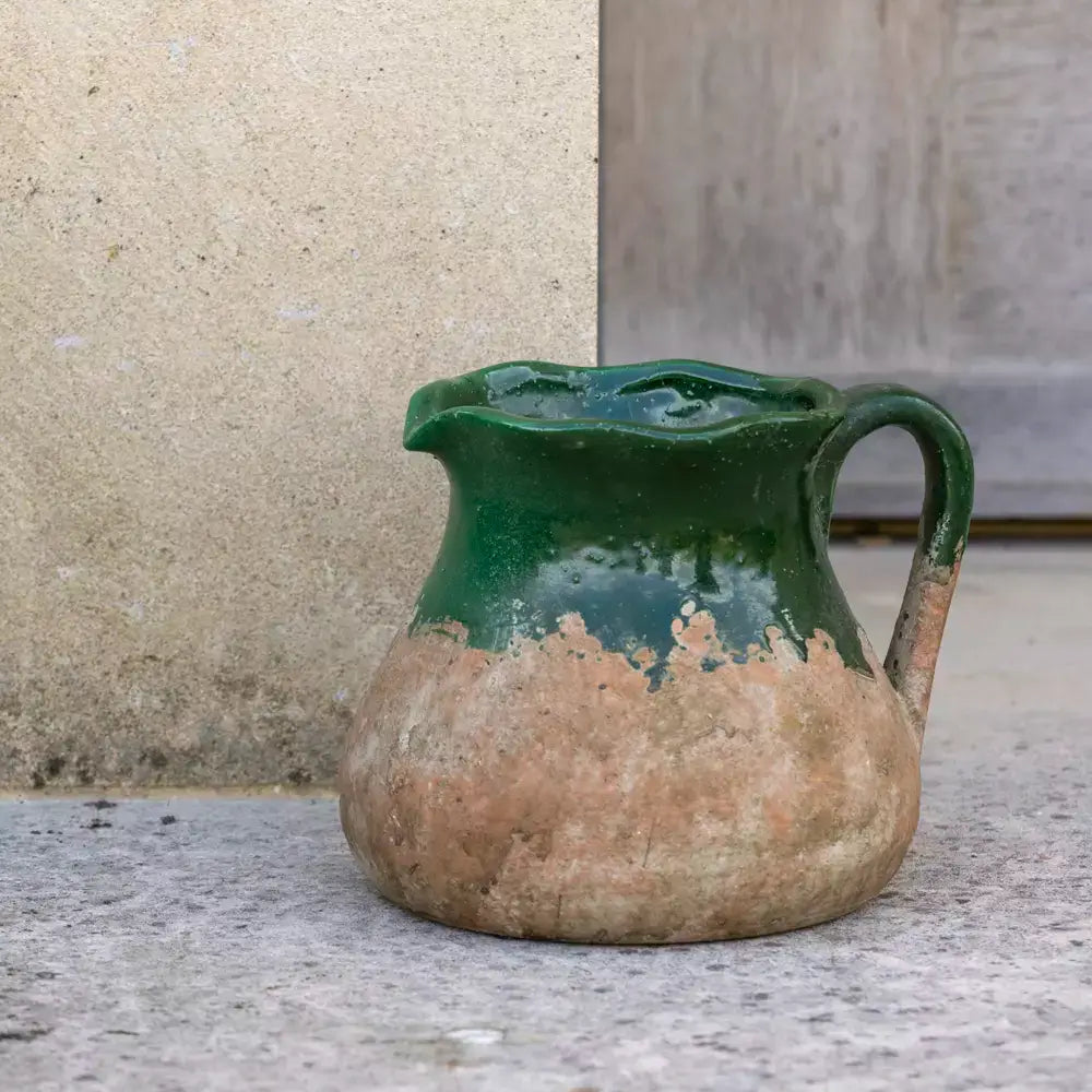 Vintage rustic green terracotta jug with earthy base and sturdy handle, perfect for decorative or practical use in home settings.