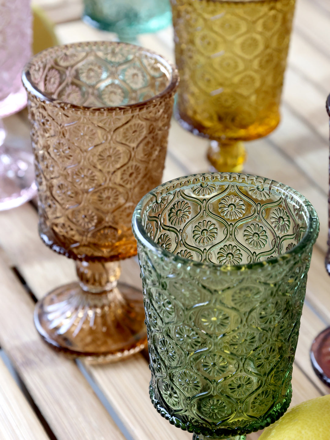 Set of six vintage style coloured wine glasses with raised designs, elegantly displayed on a wooden table. Source for the Goose Devon.