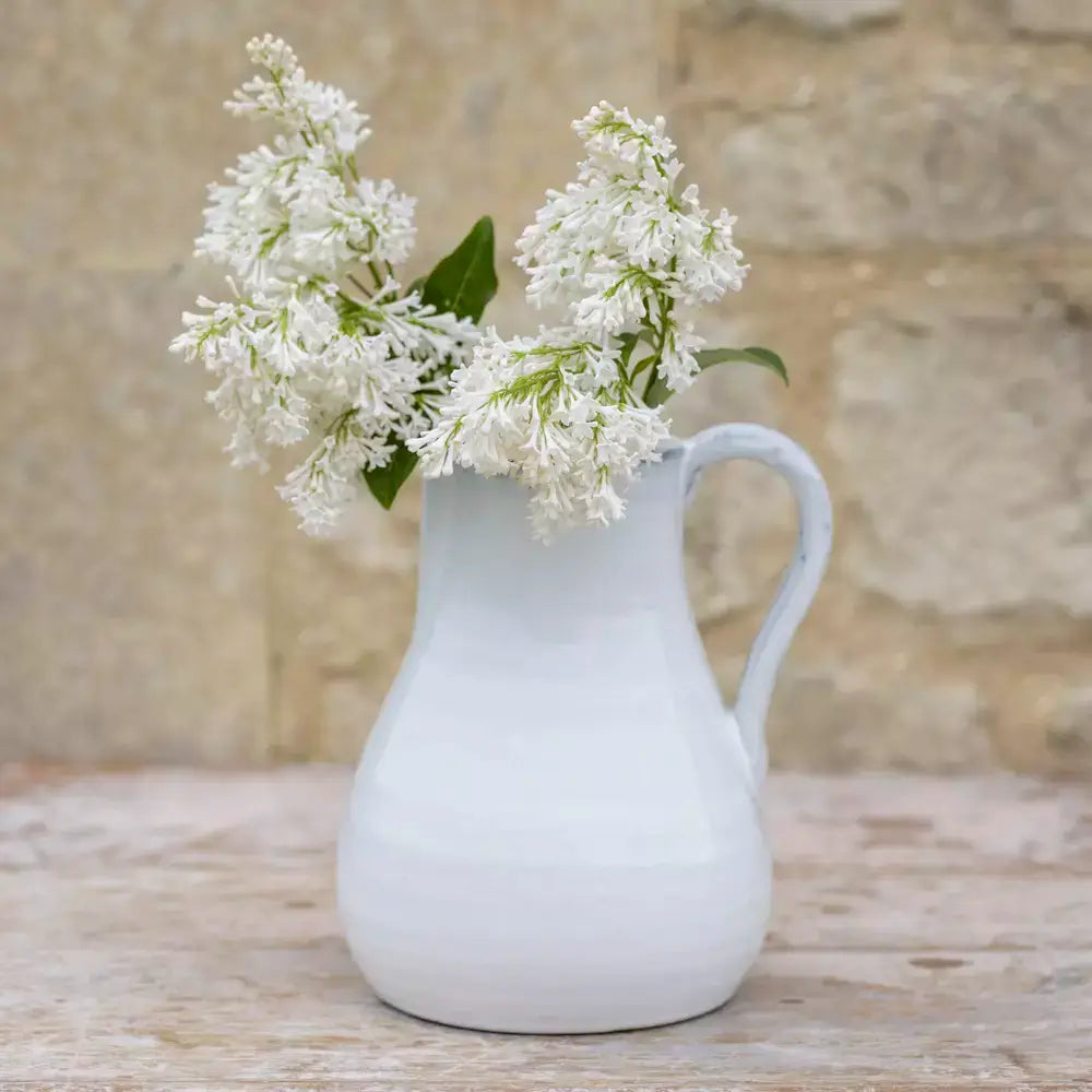 Vintage style glazed white jug with flowers, perfect for rustic home decor.