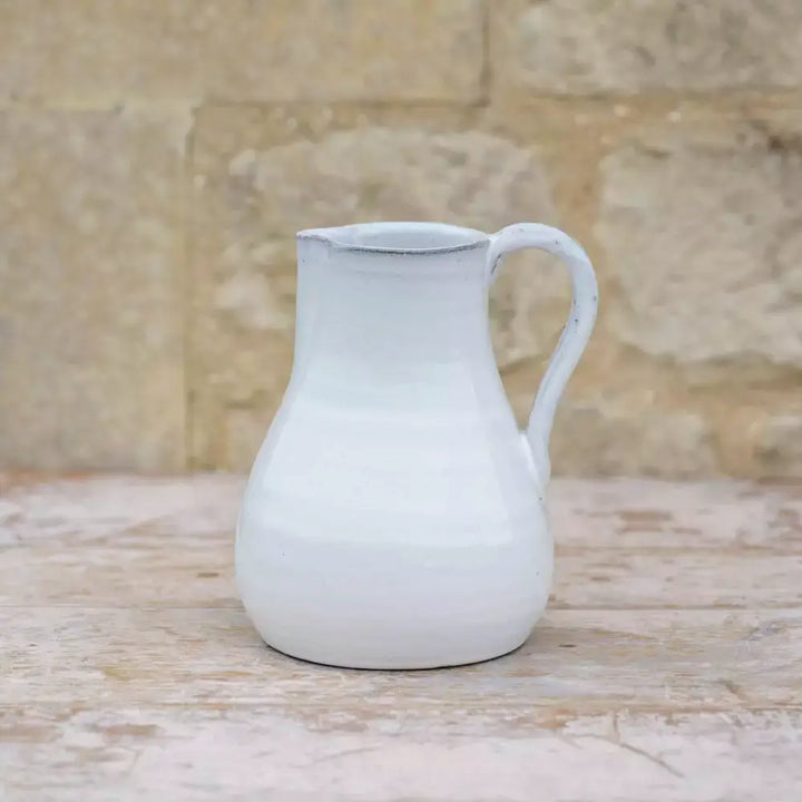 Vintage style glazed white jug with sturdy handle and spout, perfect for rustic home décor and serving beverages.