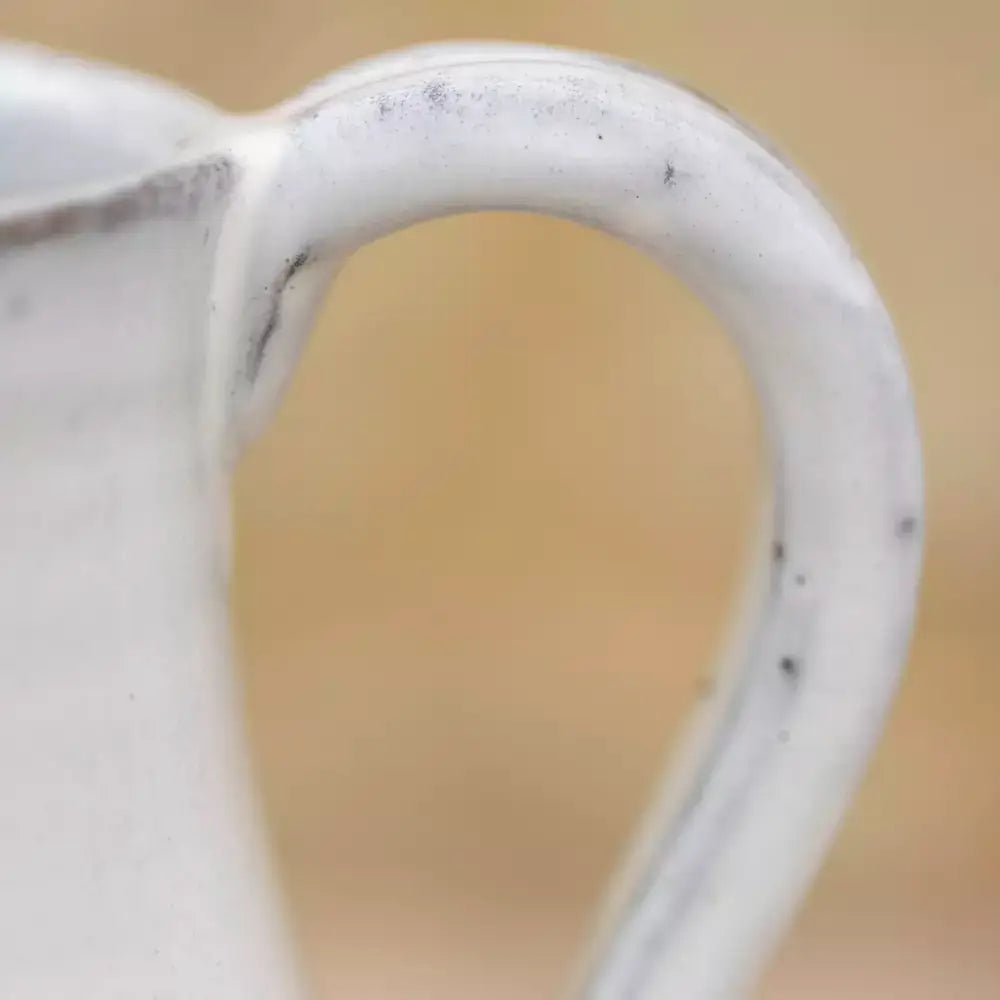 Close-up of the handle on a vintage style glazed white jug for rustic home decor.