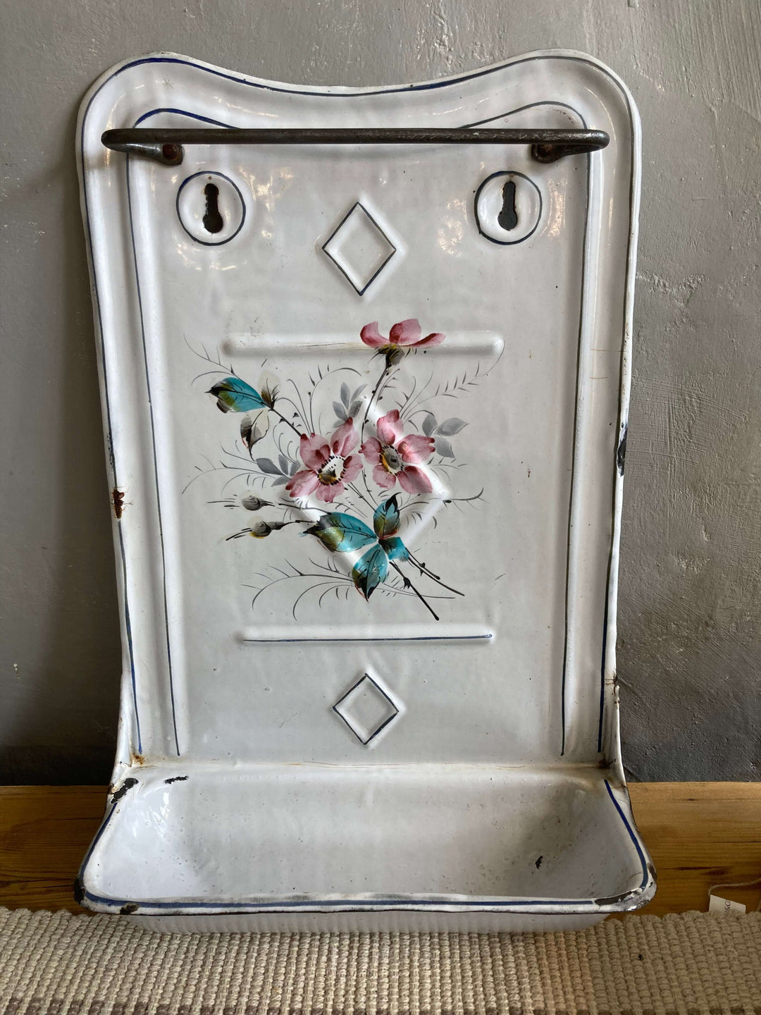 Vintage French enamel spoon rest with blue and pink floral design, rustic charm, unique design.