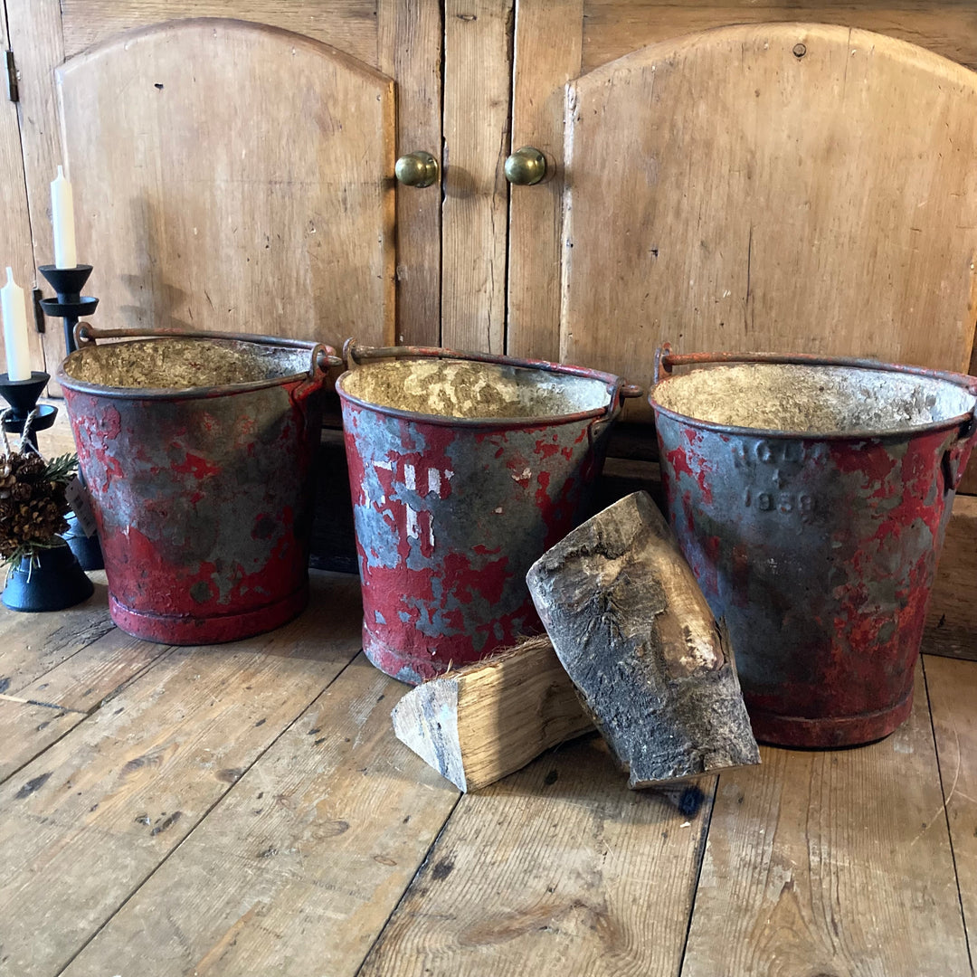 Vintage red fire buckets with distressed paint, perfect for decor or planters, sourced from Source for the Goose, Devon.