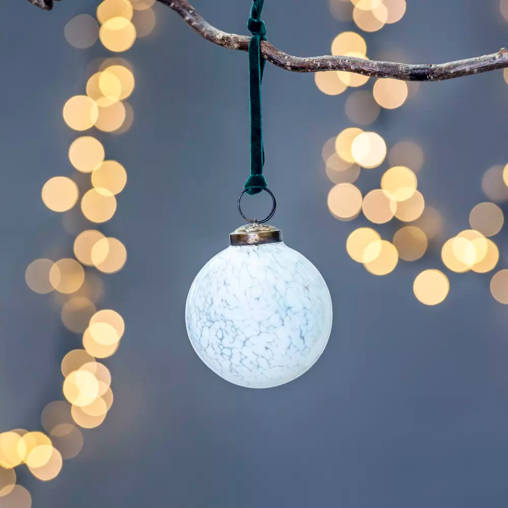 White glass Christmas decoration with teal green velvet loop hanging on a branch, featuring a pretty white mottled finish for festive decor. Source for the Goose, Devon